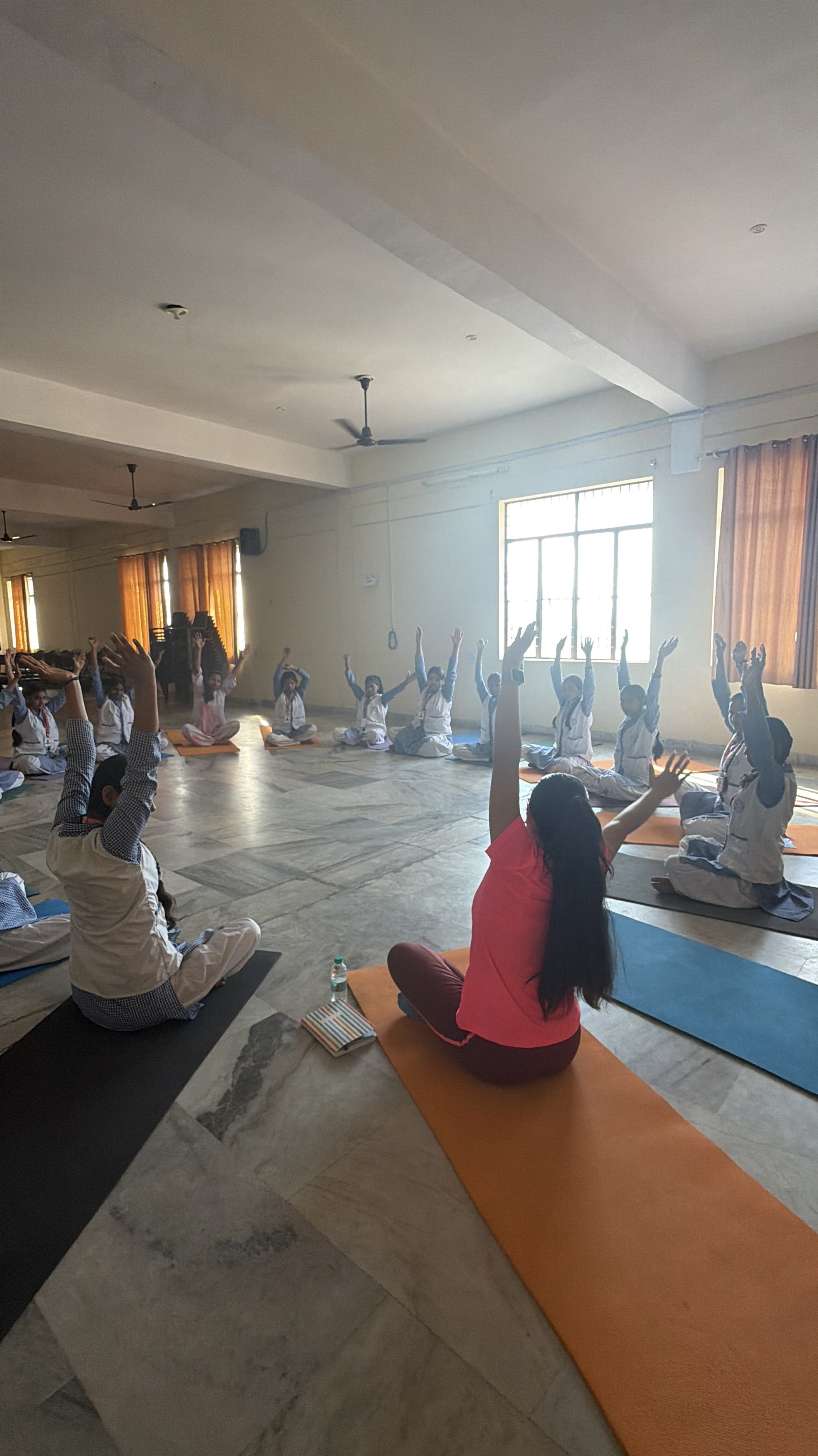 Students practicing yoga poses together in an outdoor school setting in Ferozabad